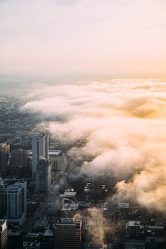 Stunning aerial view of a foggy cityscape with a dramatic sunset creating a serene atmosphere.